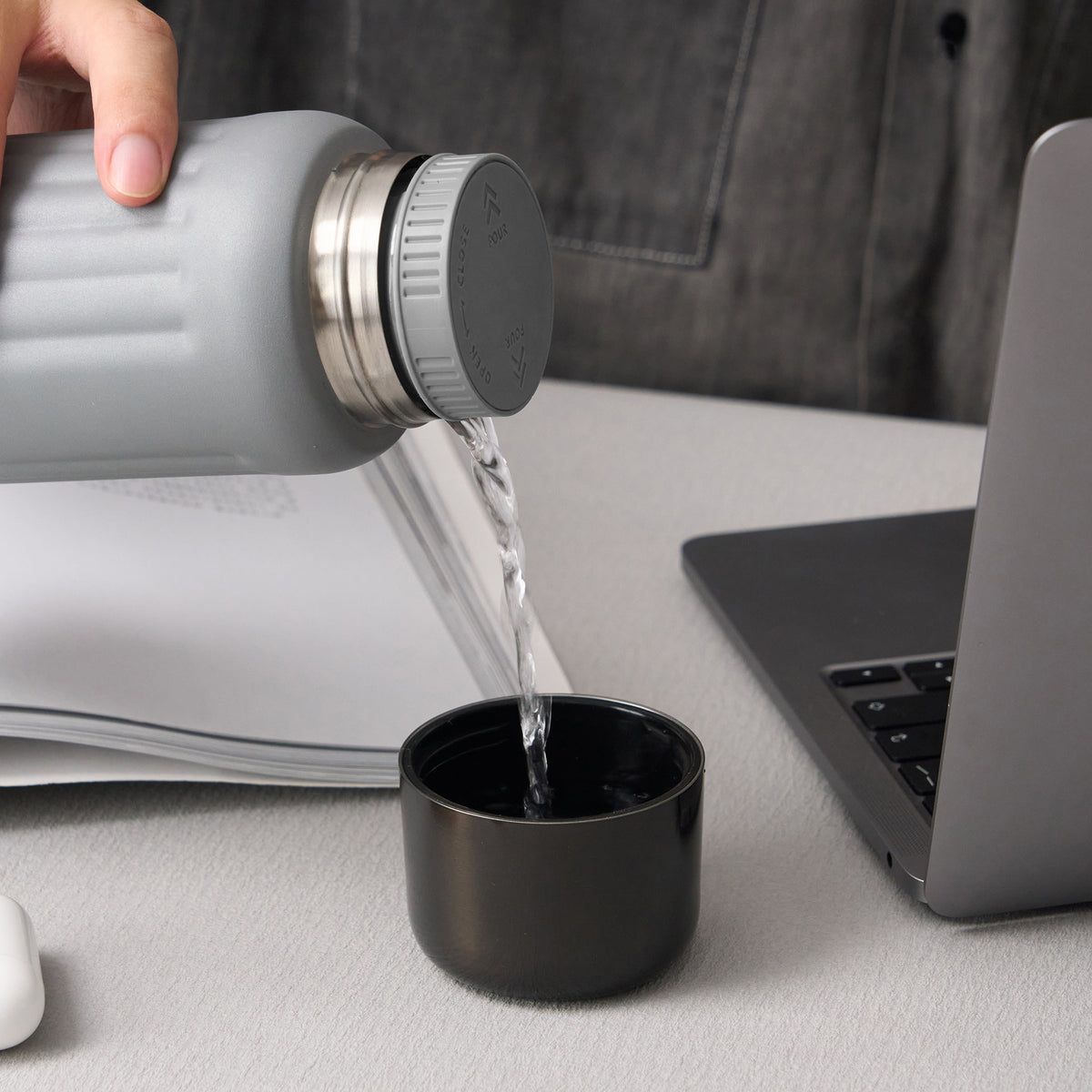 Gray FLUTE pour-through stopper in use at a desk #color_gray