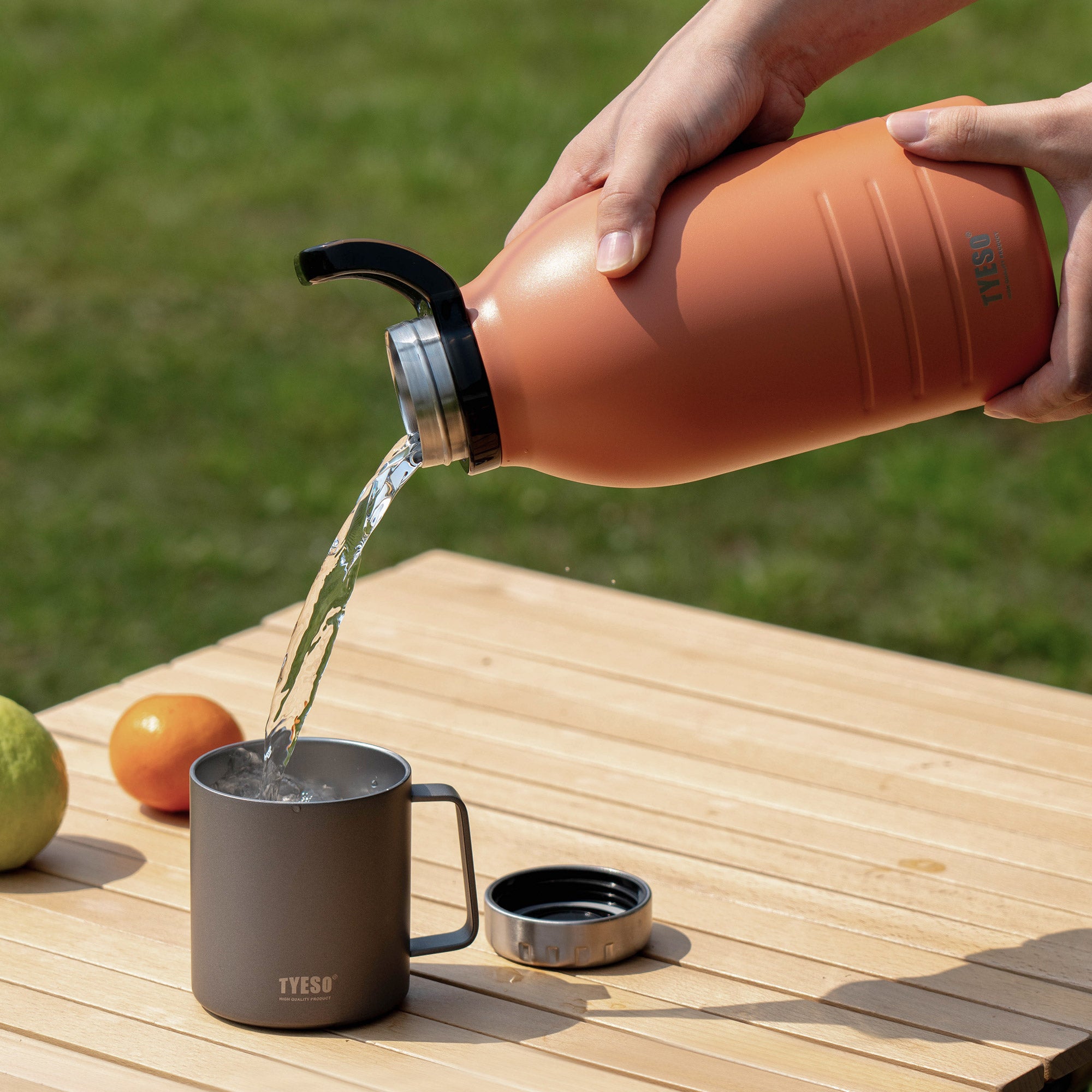 Orange 51 oz TYESO DEPOT insulated water bottle pouring water into a cup outdoors #color_orange