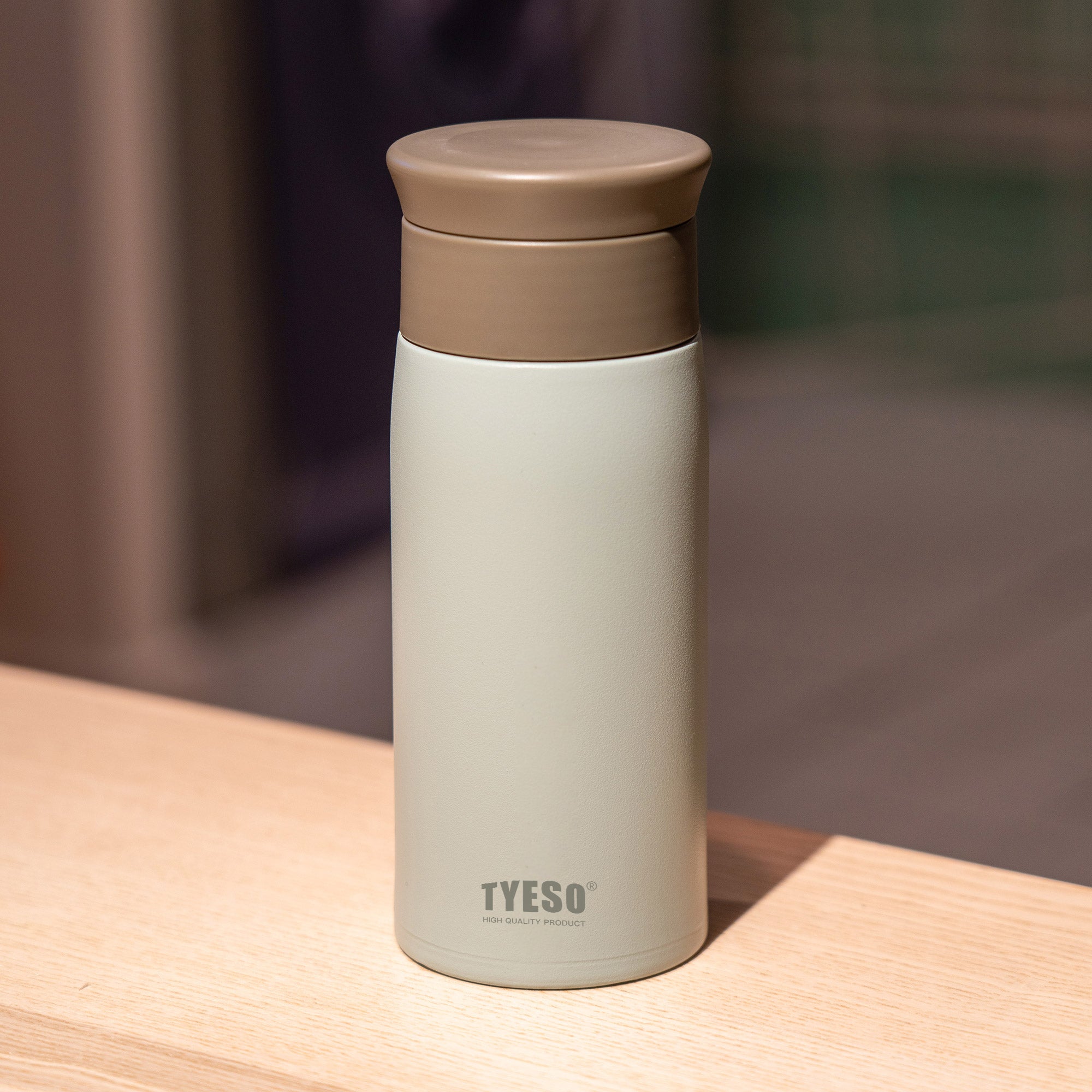 Green 12 oz TYESO LYRA insulated water bottle in a warm tabletop setting #color_green
